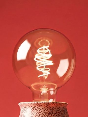 Becul cu filament spiralat pe fundal roșu